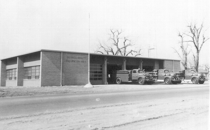 old fire trucks parked in front of a fire station
