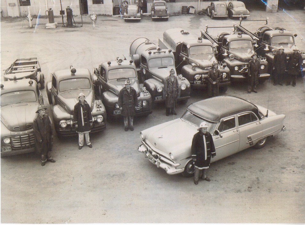 Old fire trucks with firefighters standing in front of them