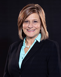 Lori Gibbs in a black blazer and teal dress shirt.